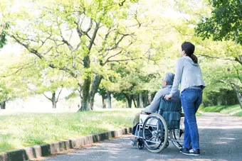 Rear view of elderly man in wheelchair and care helper